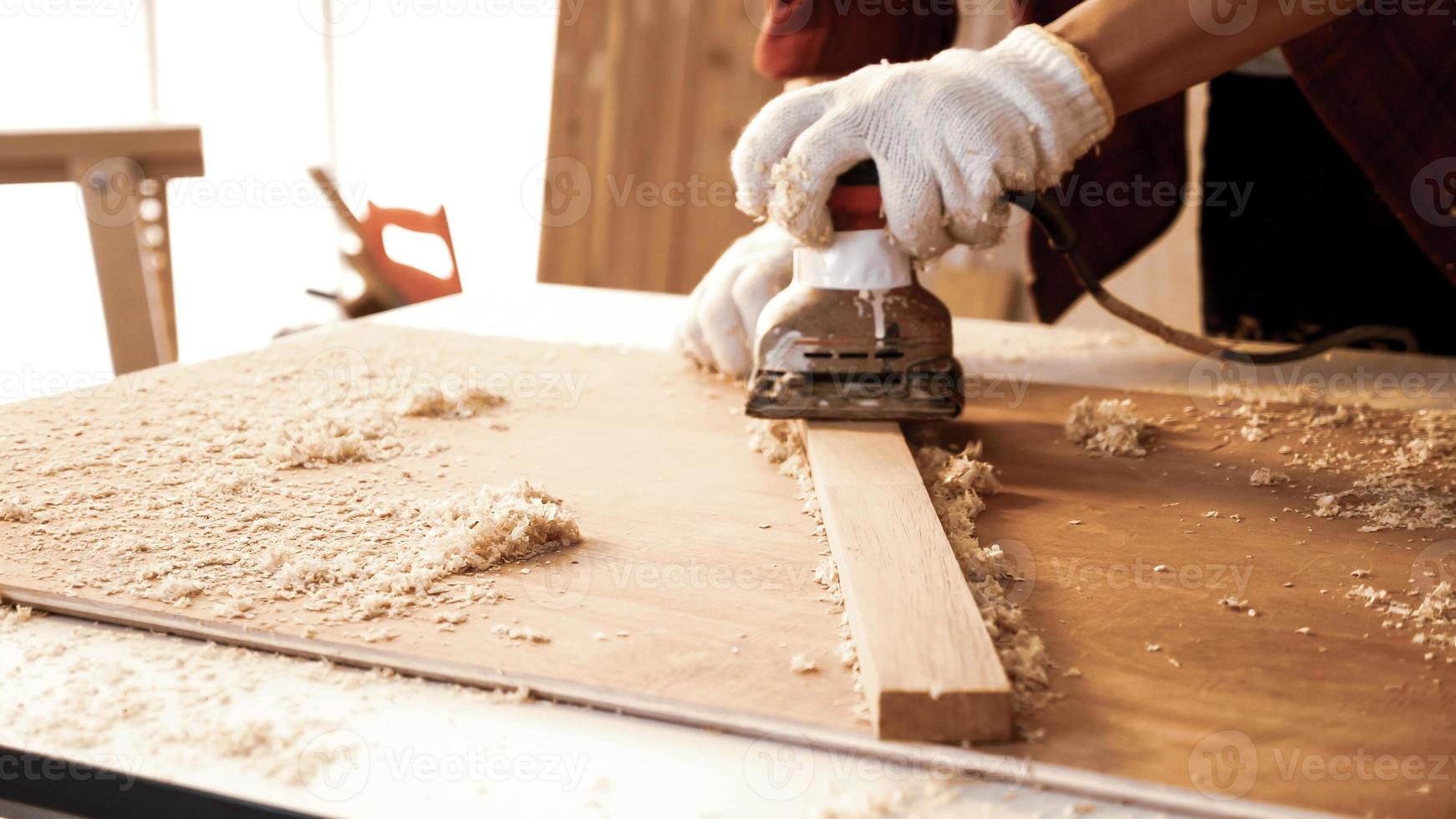 Carpenter using electric planer to shaving board at site. photo