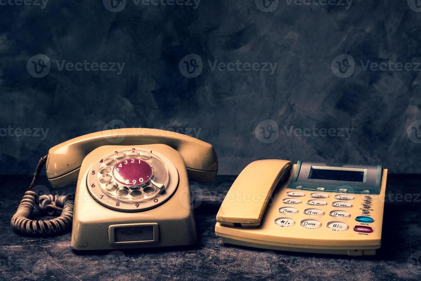 An old telephone with rotary dial and a landline on a grunge background. photo