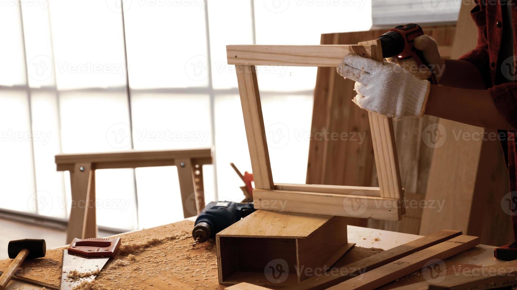 carpintero usando taladro para atornillar piezas de tablero en el sitio. foto