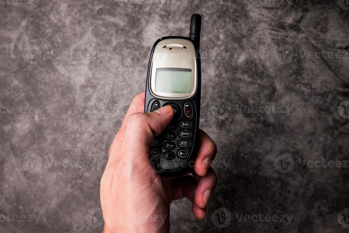 Close up of male hand press on button of an obsolete cellphone. photo