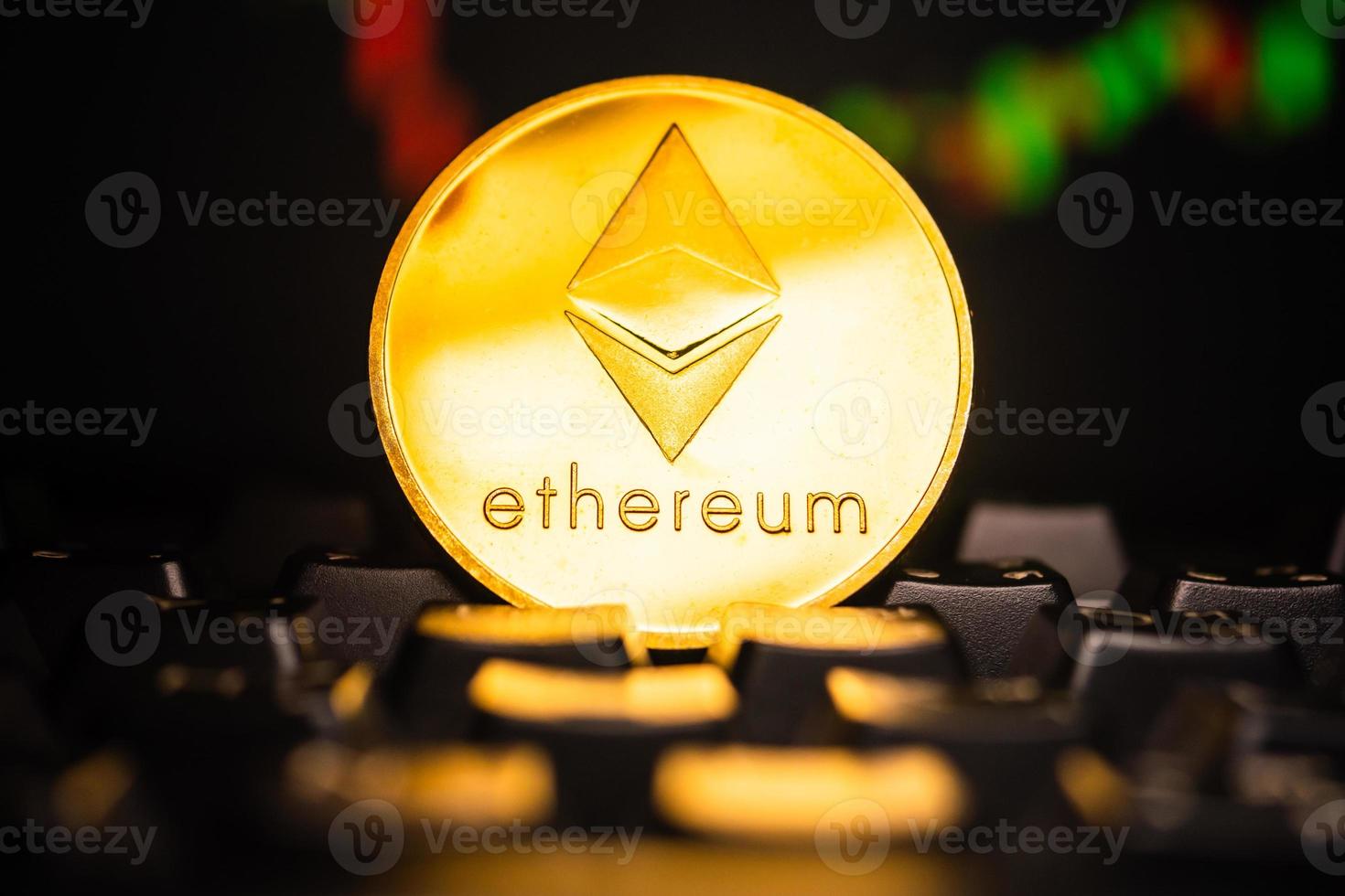 una moneda de oro con símbolo de ethereum en el teclado de la computadora con fondo de gráfico de acciones. foto