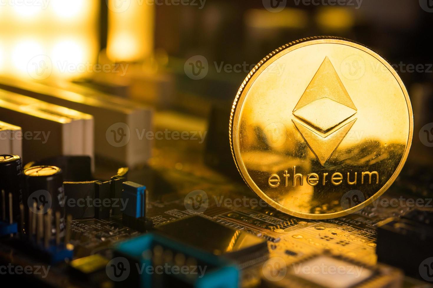 A golden coin with ethereum symbol on a mainboard. photo