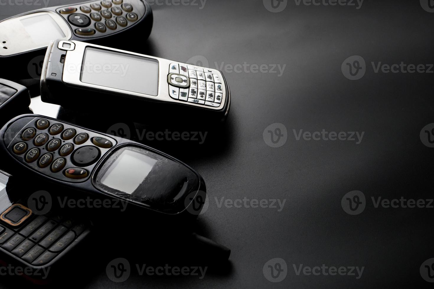 Old and obsoleted cellphones on a black background. photo