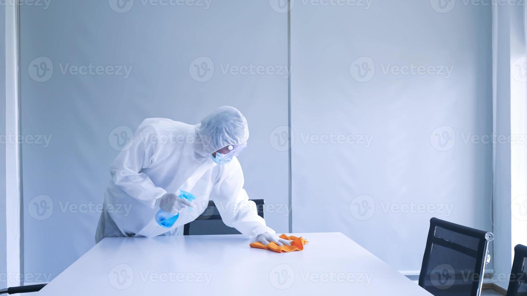 Worker in personal protective equipment suit cleaning in building with spray disinfectant water to remove covid 19 photo