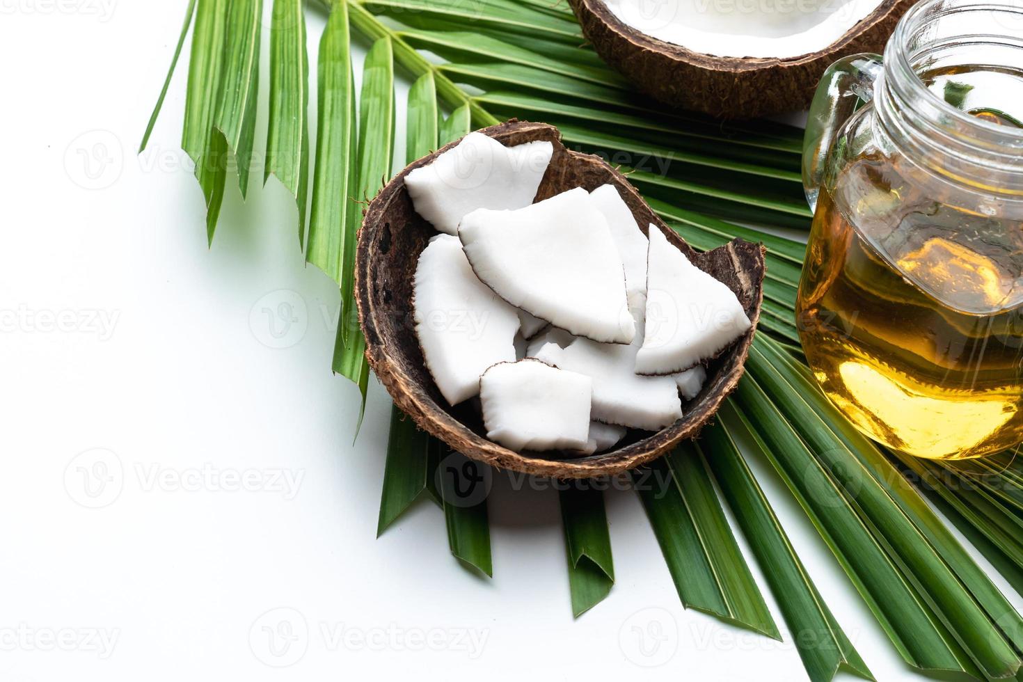 Coconut meat and coconut oil in glass bottle on coconut leaf. photo