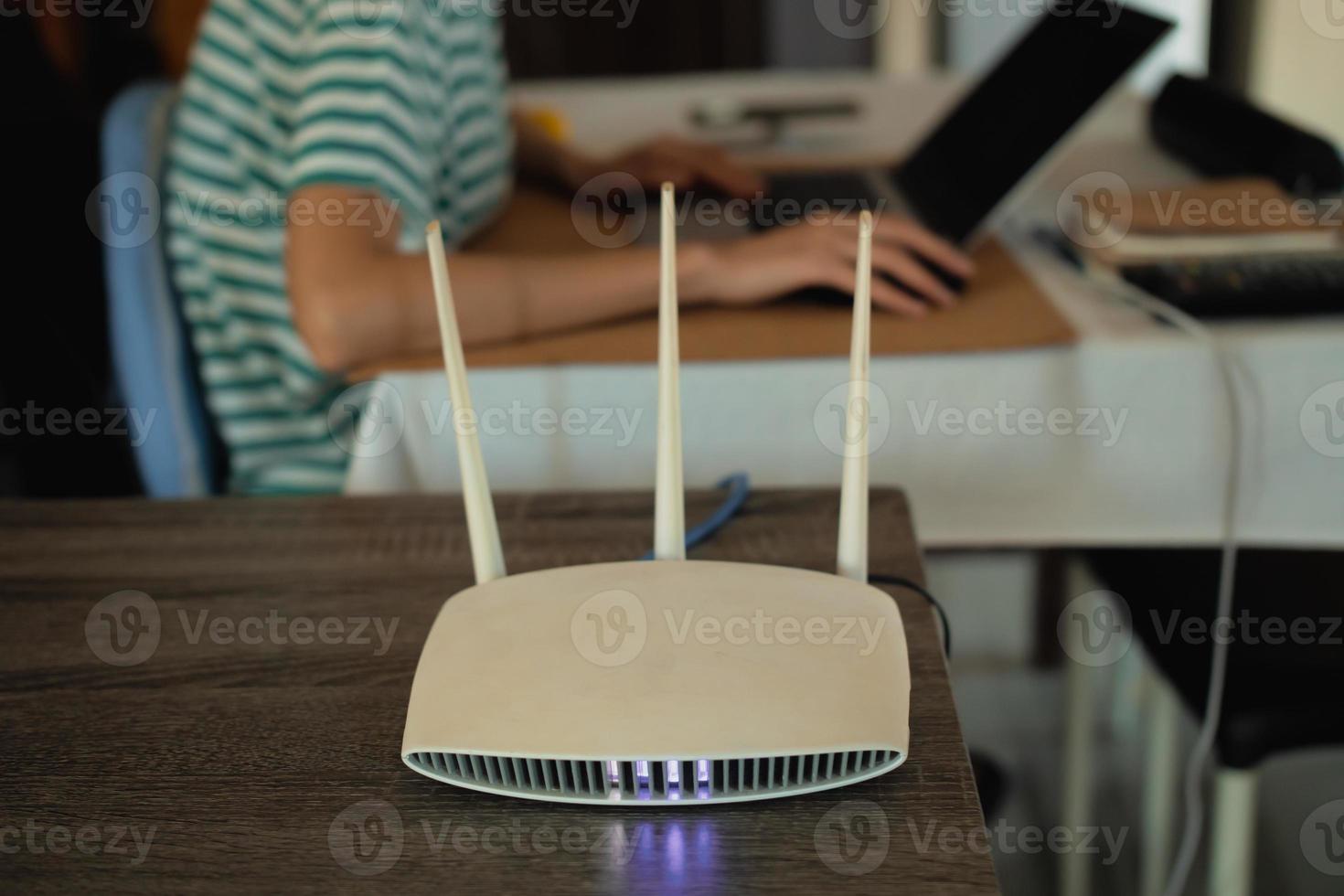 A woman is working at home using a modem router, connecting the Internet to her laptop. photo