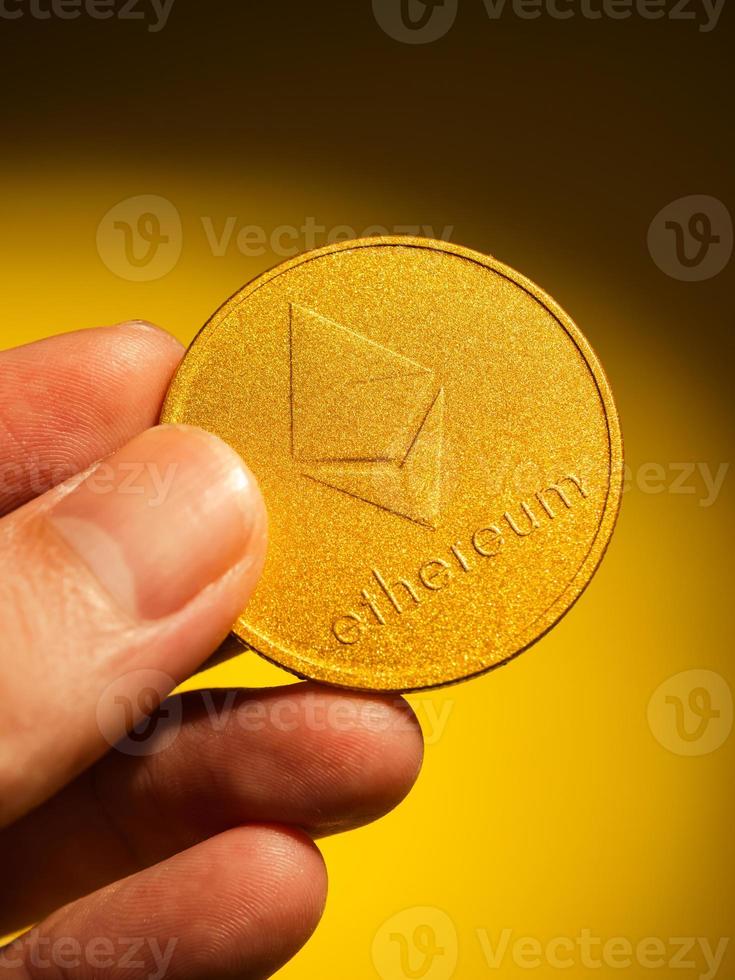 Hand holding golden coin with ethereum symbol.  Digital currency concept. photo