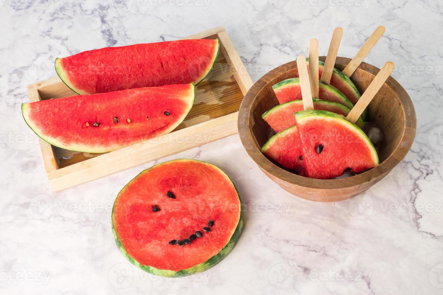 Watermelon slices on sticks with ice cubes. Fresh watermelon popsicles in wooden bowl. photo