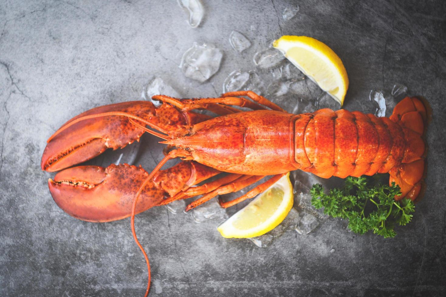 comida de langosta fresca sobre un fondo de plato negro cena de langosta roja mariscos con hierbas especias limón servido mesa y hielo en el restaurante comida gourmet saludable langosta hervida cocida foto