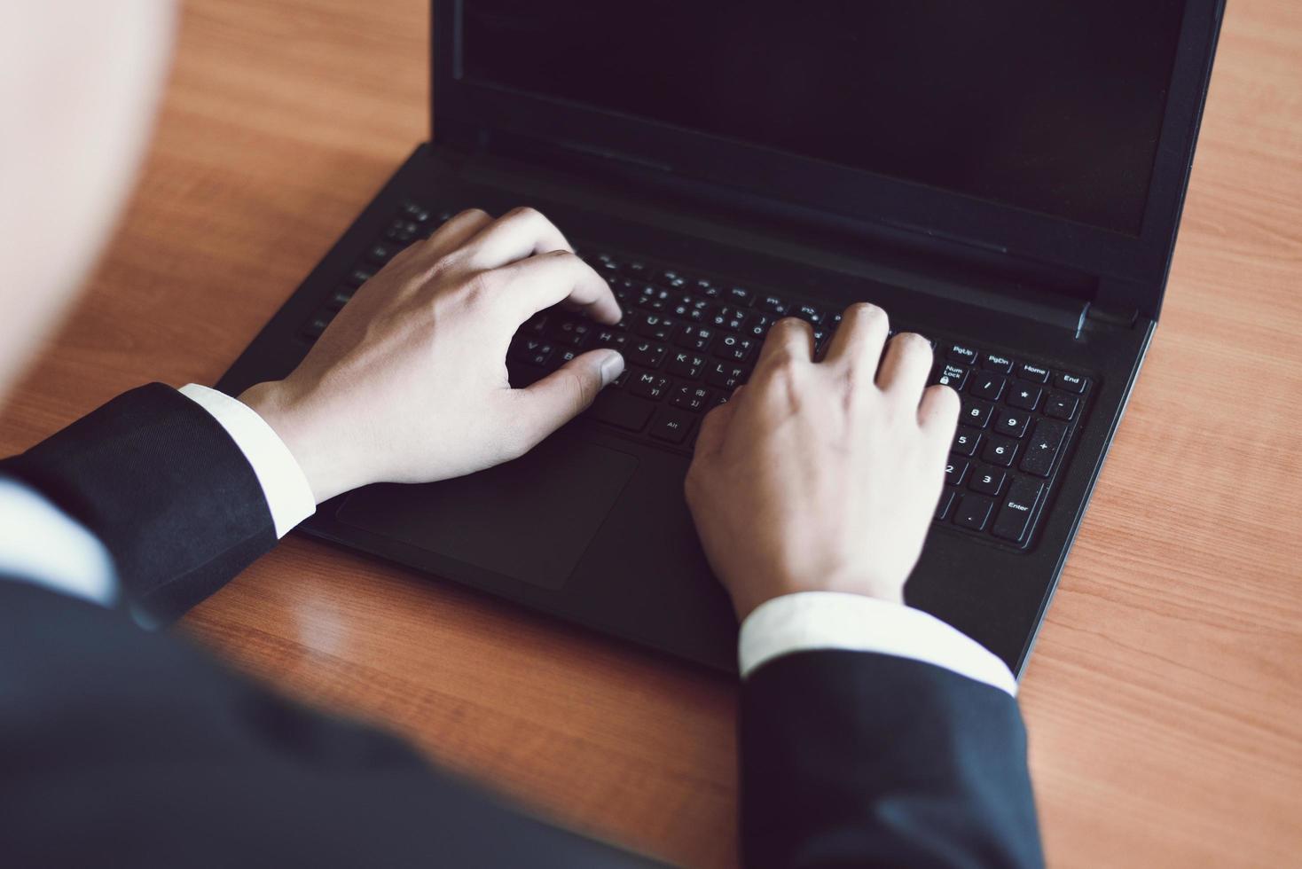 Businessman working on keyboard computer laptop man sitting on the table and using internet technology at workplace in office - Male hand typing on keyboard concept photo