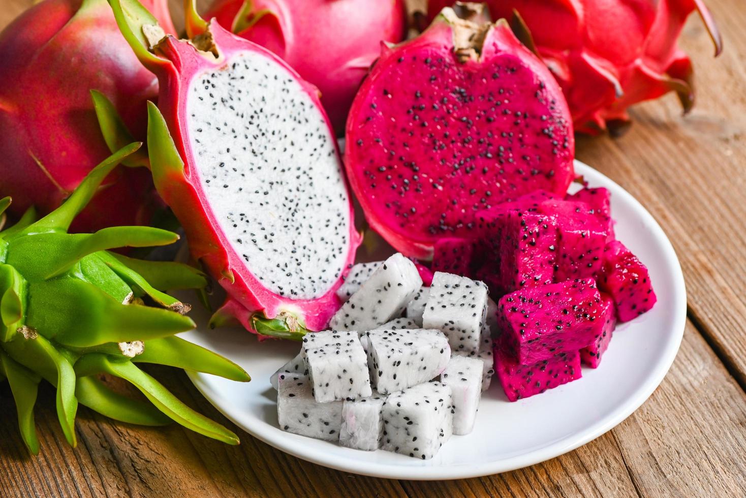 fruta de dragón púrpura blanca y roja fresca tropical en el concepto de fruta saludable de tailandia asiática, rebanada de fruta de dragón y mitad cortada en un plato blanco con fondo de pitahaya foto