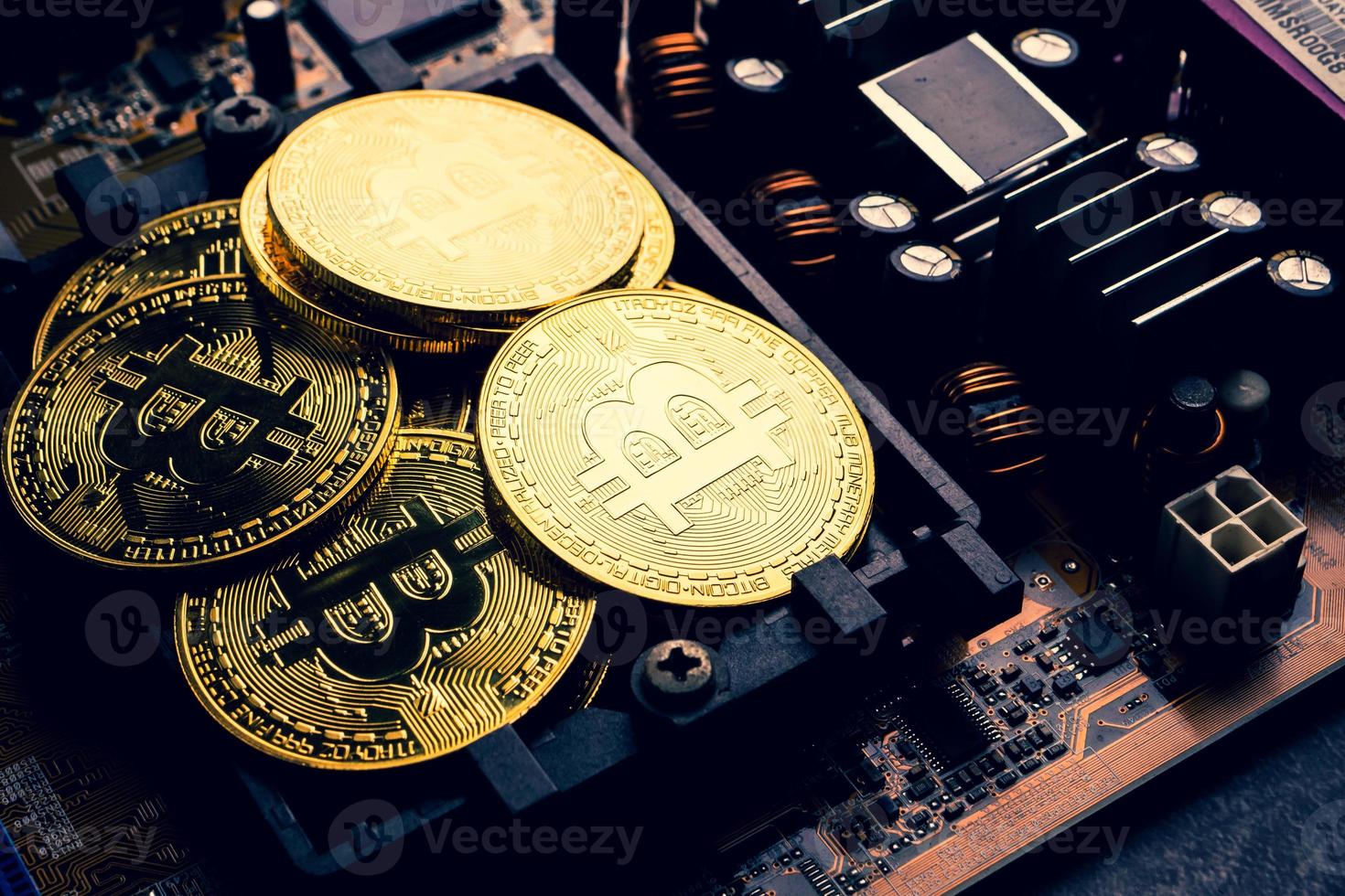 Golden coins with bitcoin symbol on a mainboard. photo