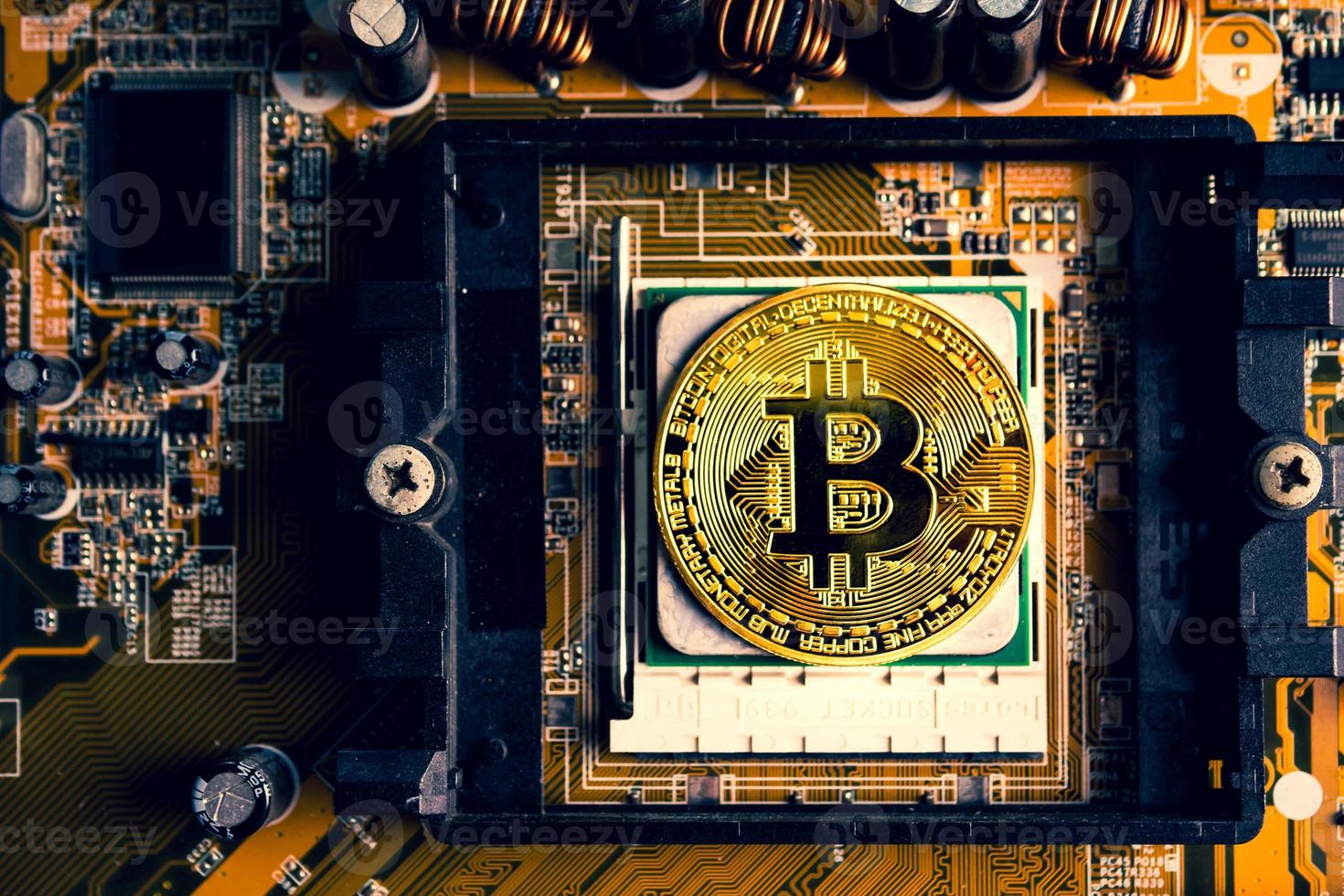 A golden coin with bitcoin symbol on a mainboard. photo