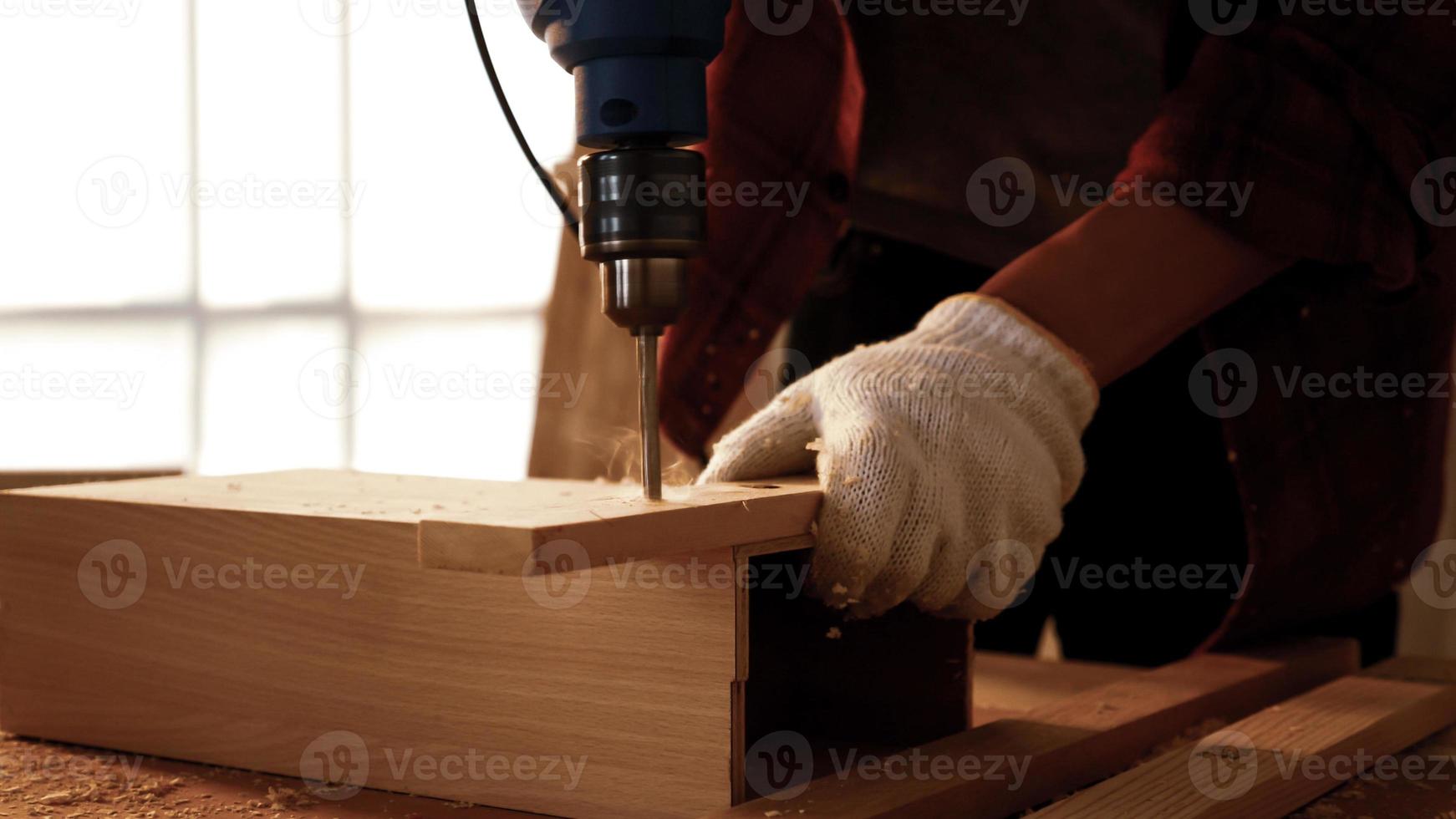 Carpenter using drill to screwing pieces of board at site. photo