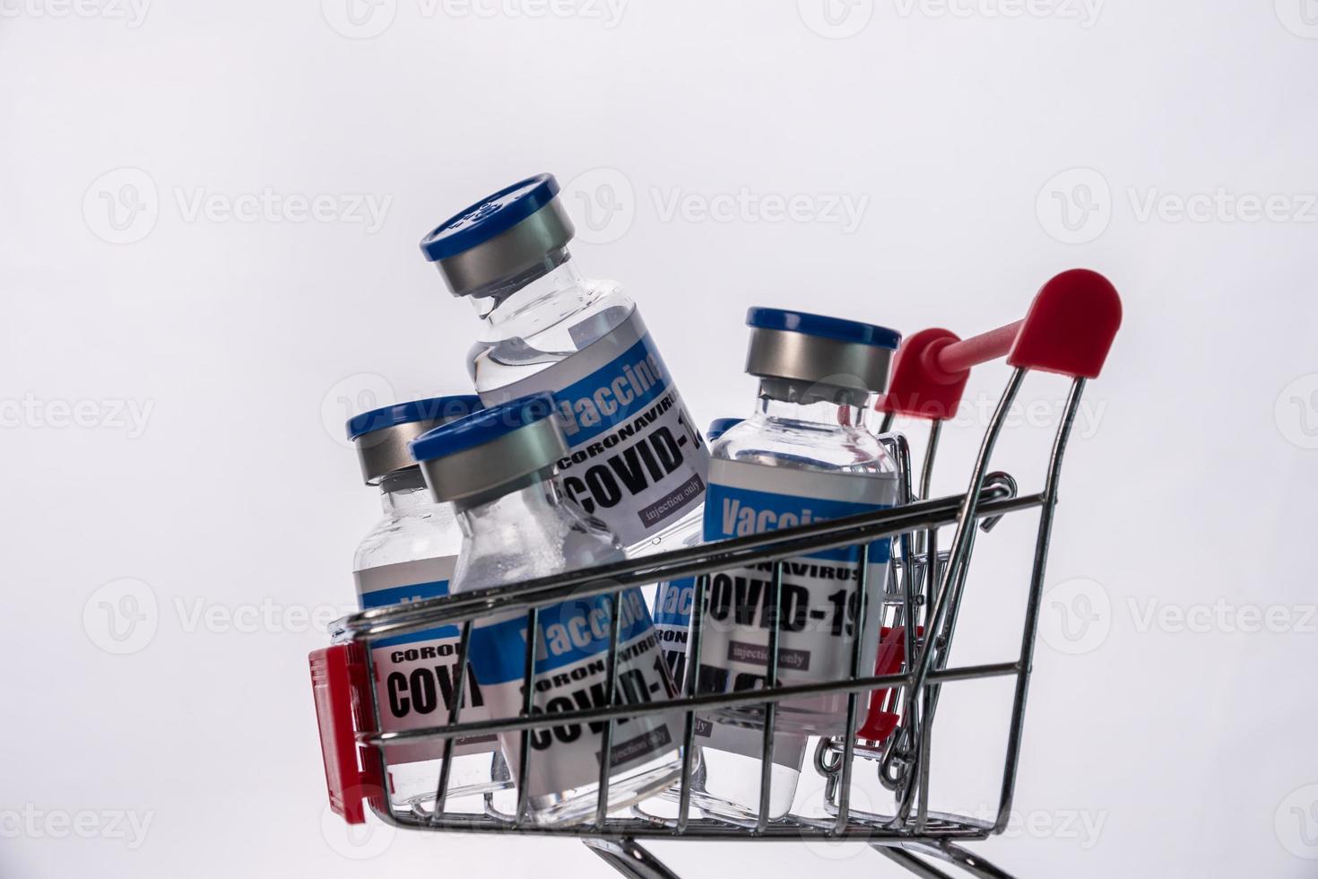 Glass vials for Covid-19 vaccine in shopping cart on white background. Group of Coronavirus vaccine bottles in basket. photo