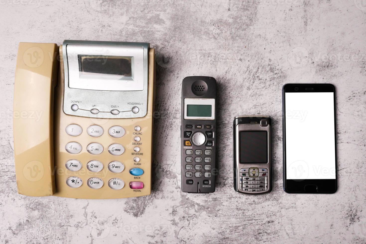 A landline, an obsoleted cellphone and smartphone on a grunge background. photo