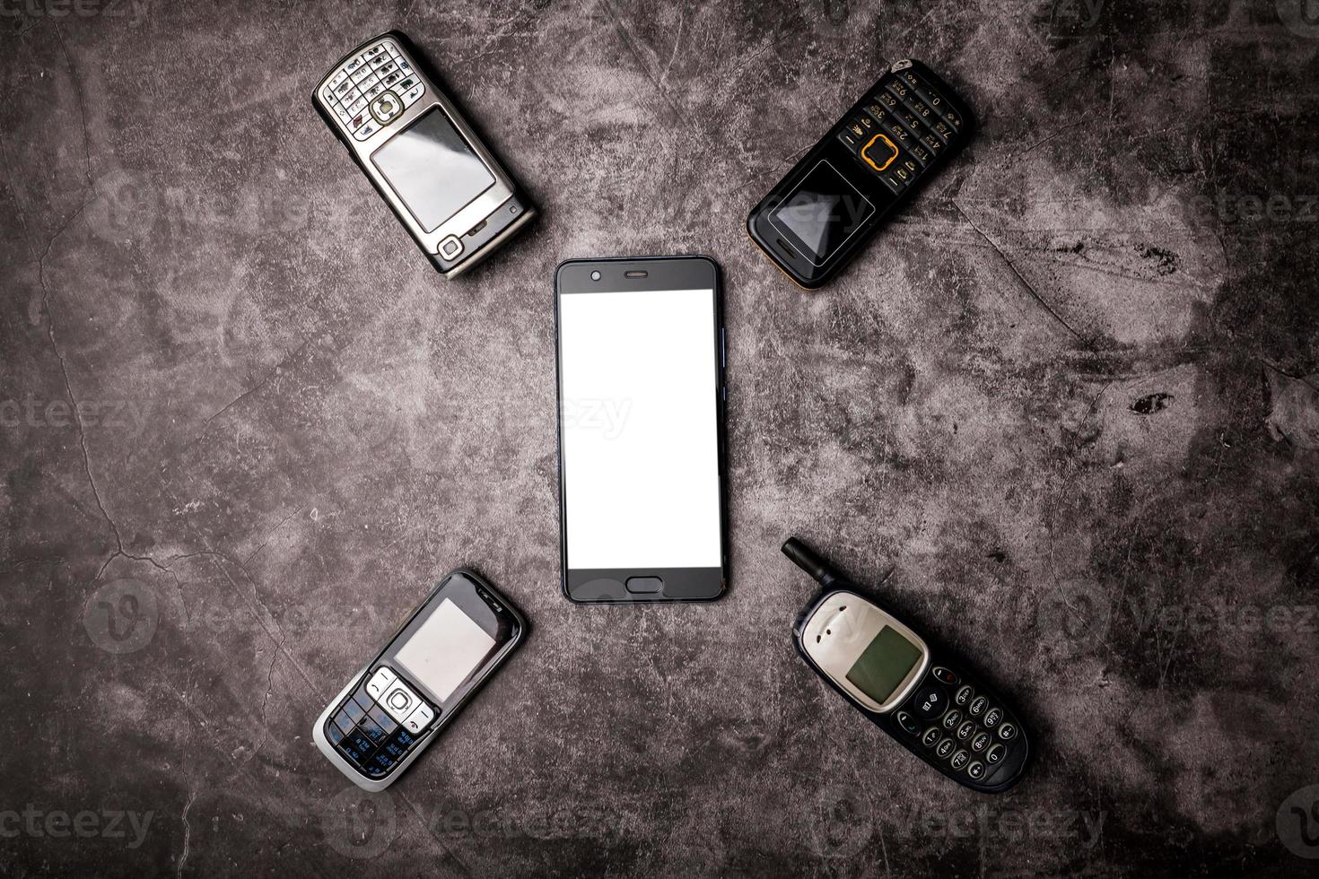 Many obsoleted cellphones and a smartphone on a grunge background. photo