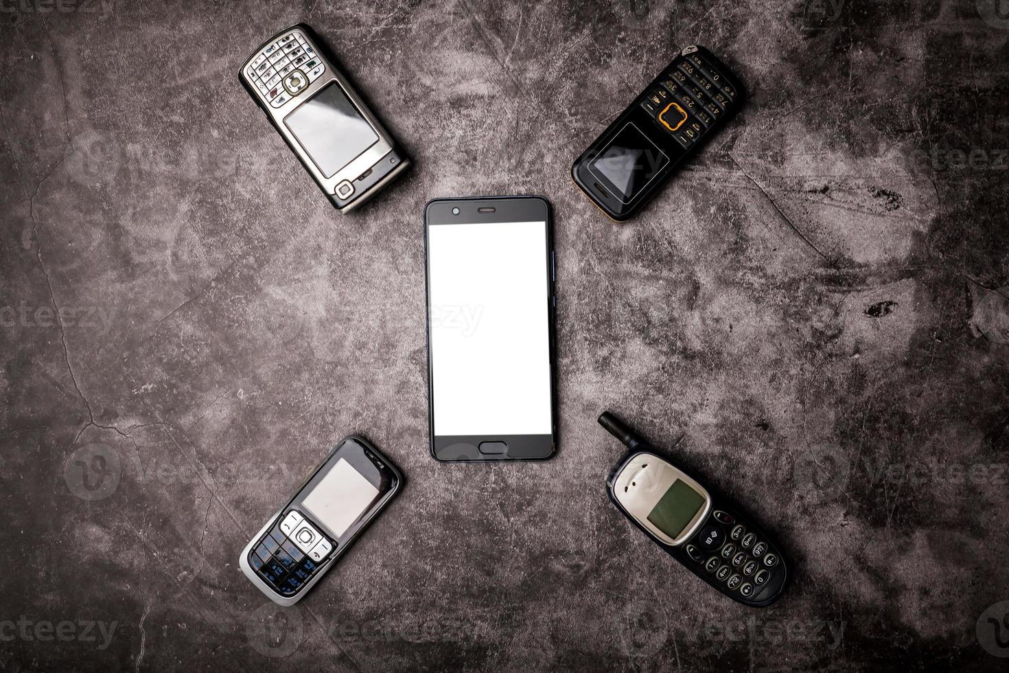 muchos teléfonos celulares obsoletos y un teléfono inteligente en un fondo grunge. foto