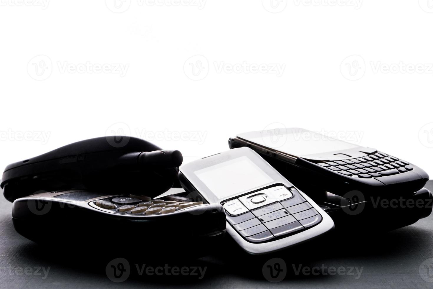 Old and obsoleted cellphones on a black background. photo