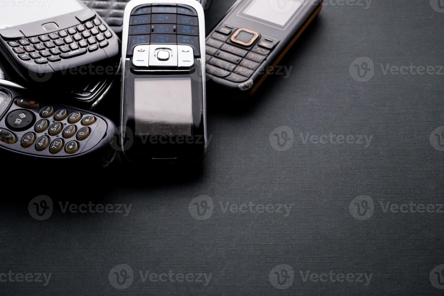 Old and obsoleted cellphones on a black background. photo