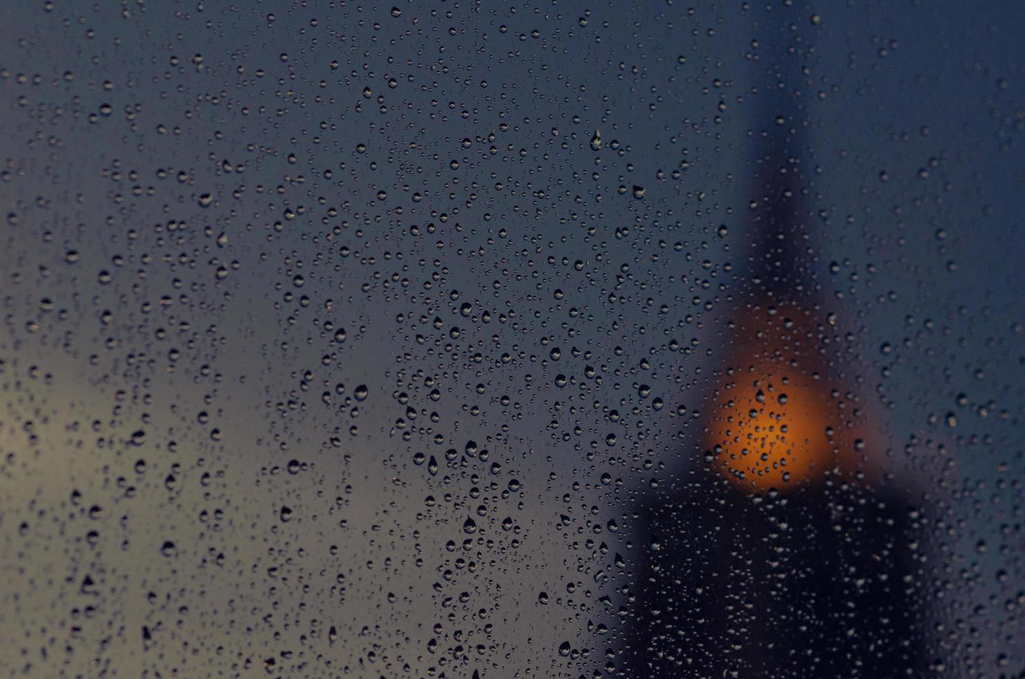 Partial focus of rain drop on glass window in monsoon season with blurred  pagoda of temple  background. photo