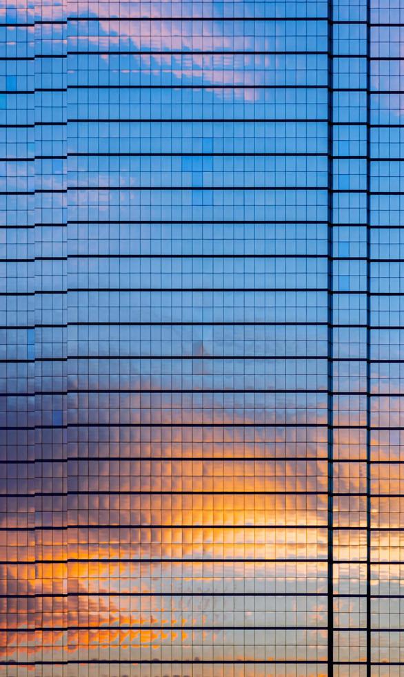 The building covers with glasses that have reflection from dusk sky and cloud on it. photo