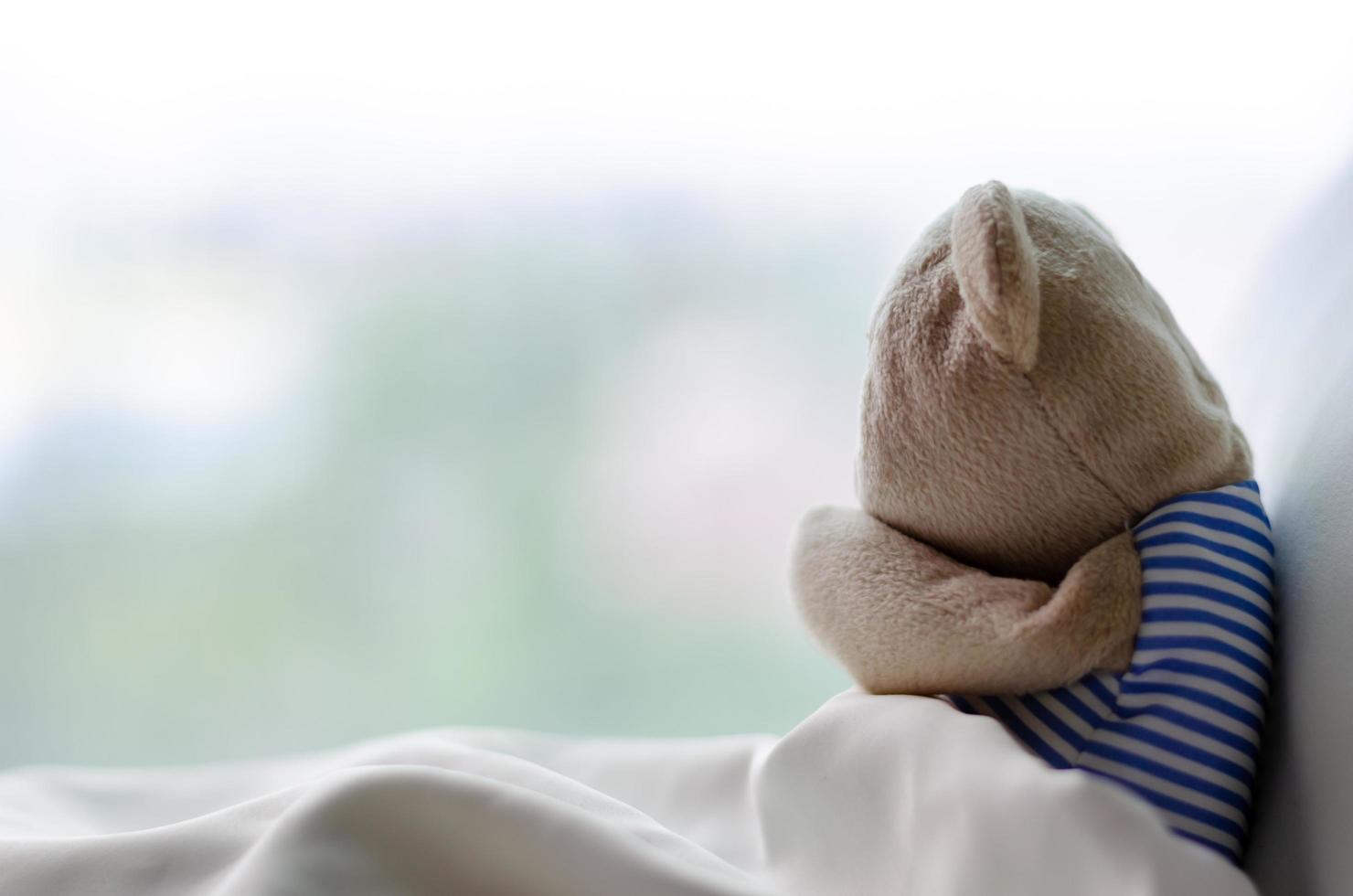 Teddy bear sobbing on bed in the sadly day. photo