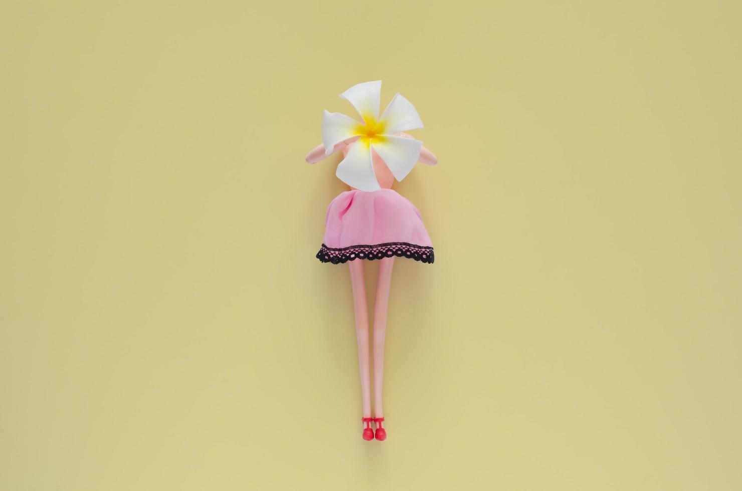 Female doll holding Frangipani flower. Minimal beauty and fashion concept. photo