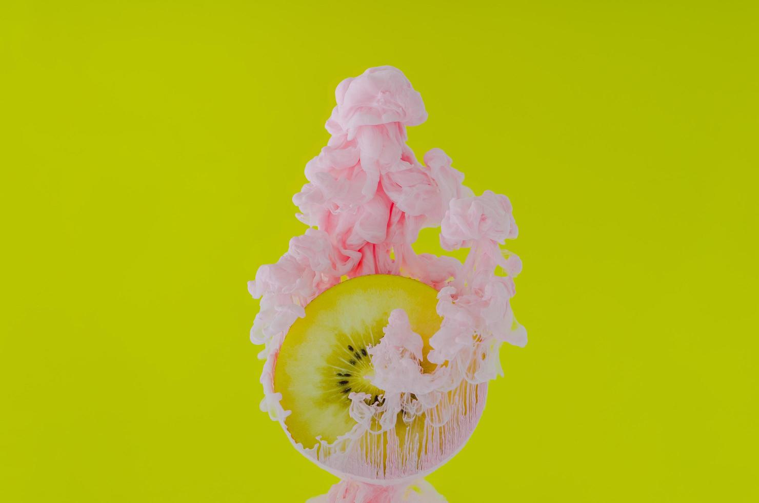 Slice kiwi fruit with partial focus of dissolving pink poster color photo