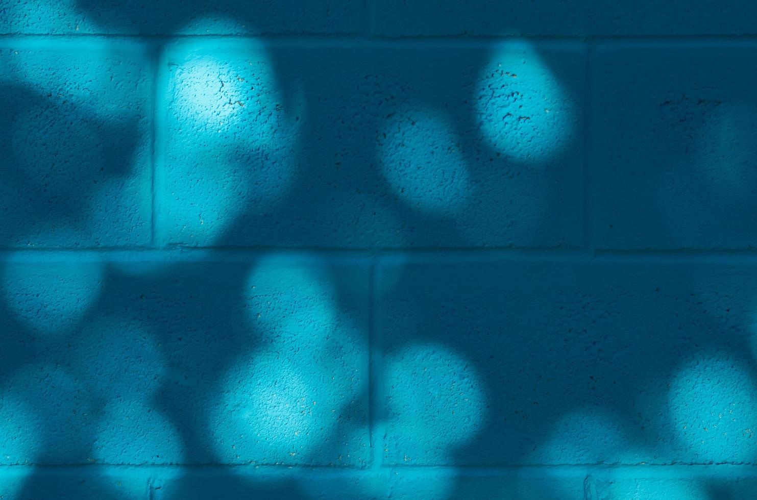 Muro de hormigón pintado de azul con sombra del árbol. foto