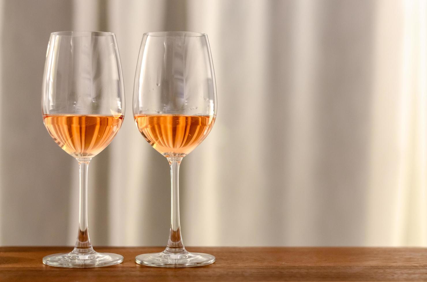 dos copas de vino rosado en una mesa de madera para celebrar en pareja. foto