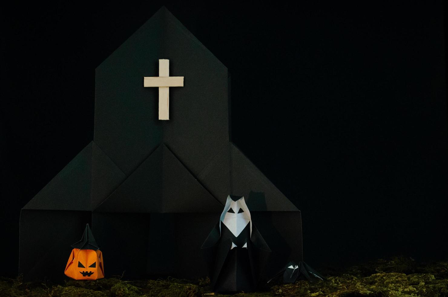 The Halloween background of origami or Paper folding that the nun standing in front of black church with jack o lantern and spider with messy lawn on black background. photo