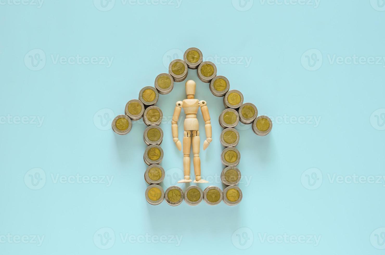 Wood model stays in the middle of Thai baht coins that set as home symbol. photo