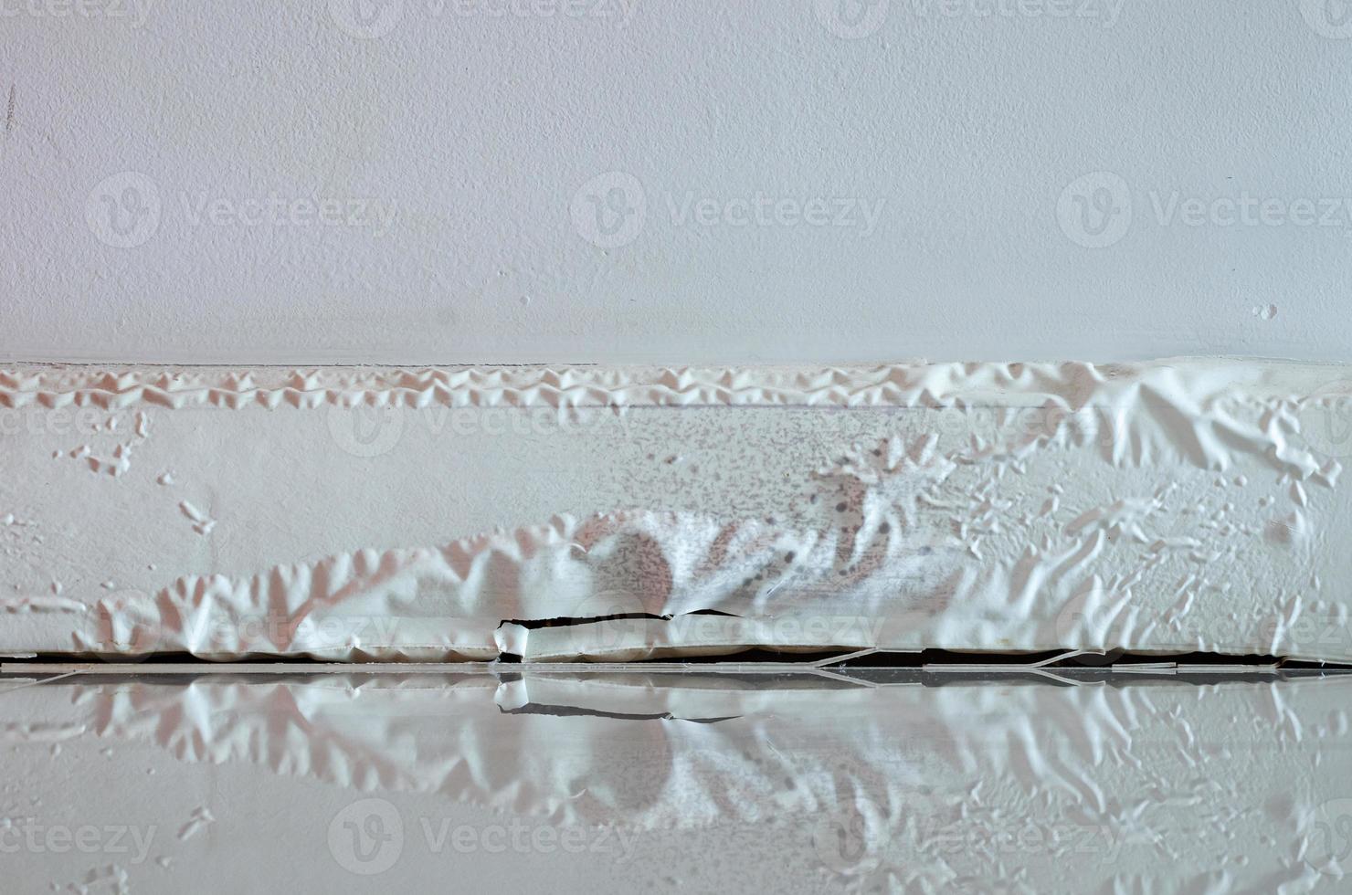 White skirting board damaged by destructive elements from moisture or water. photo