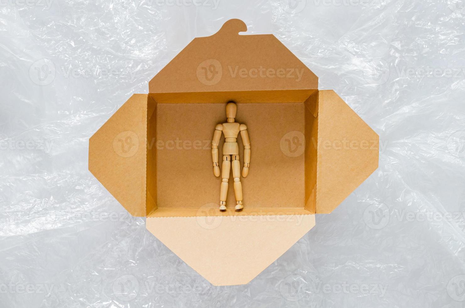 Wooden model stay safe inside disposable, compostable paper food box that surrounding with plastic bag. World environment day concept. photo