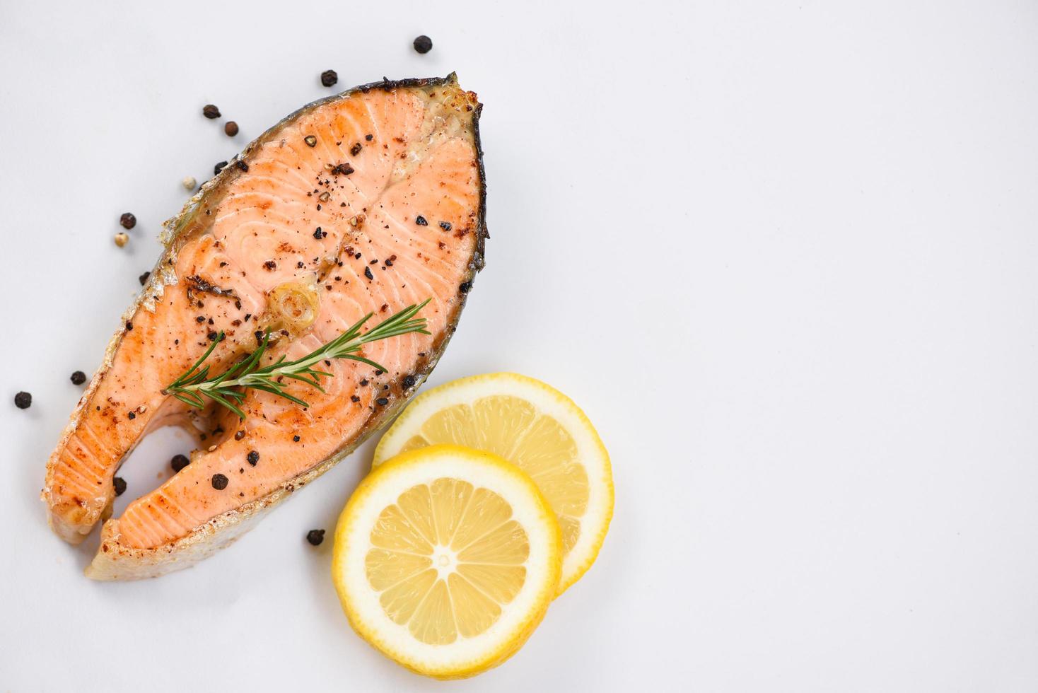 Grilled salmon steak with herbs and spices rosemary lemon on plate background Close up cooked salmon fish fillet steak seafood photo