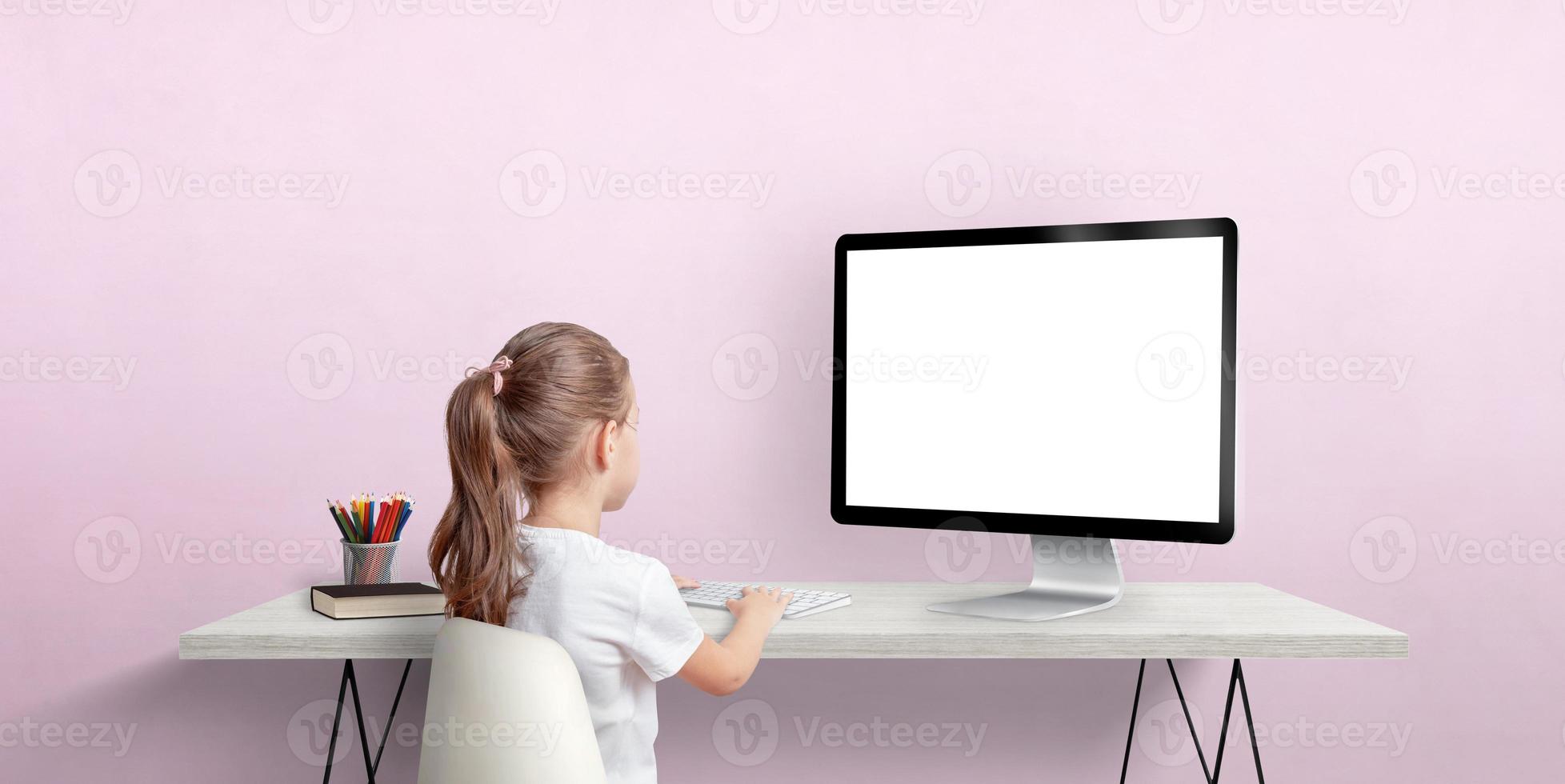 Young girl work on computer concept. Isolated computer display for mockup. Work room with pink wall. Back view photo