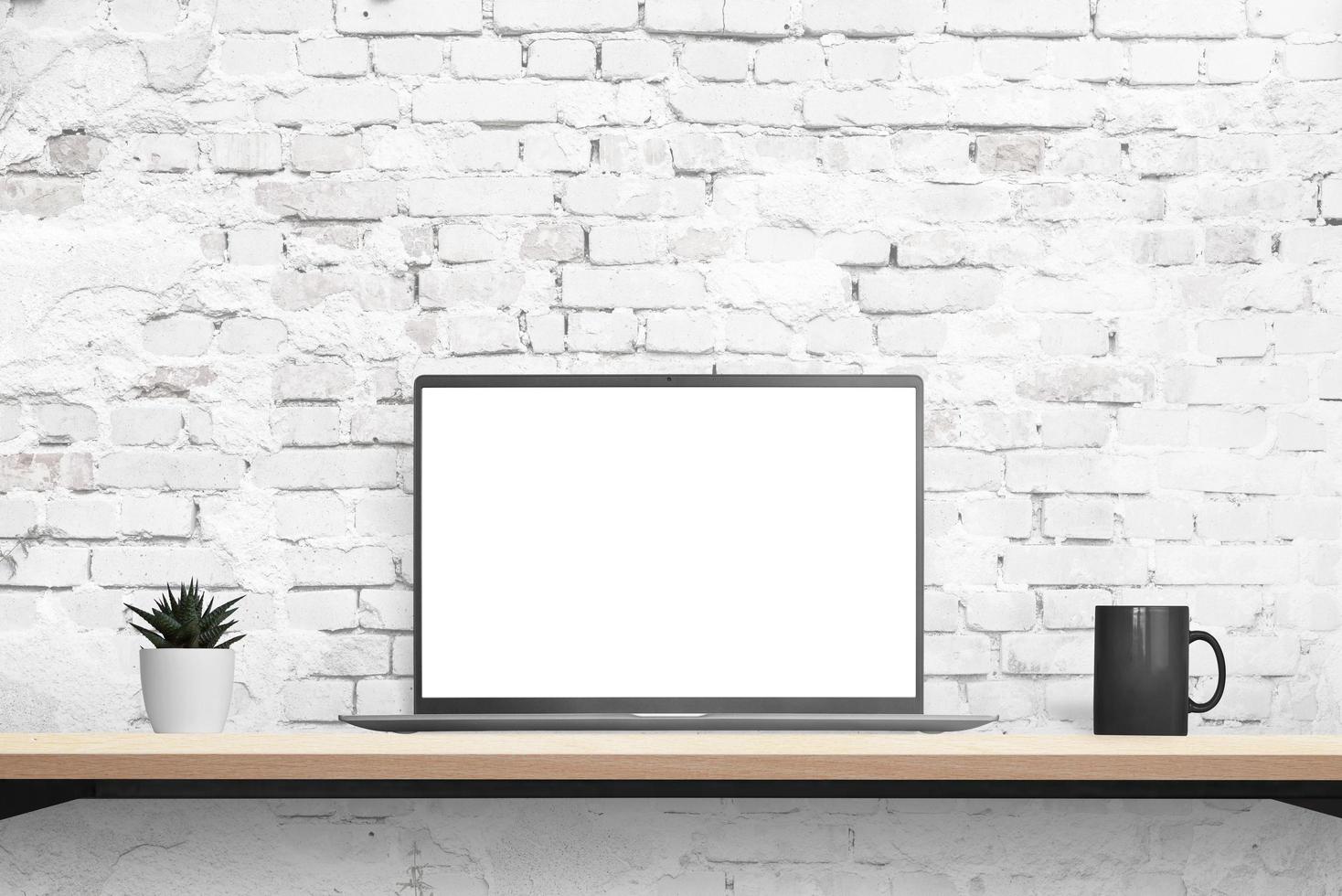 Laptop mockup on desk with brick wall in background. Isolated displaz in white for mockup, app or web page promotion. Plant and coffee mug beside. Front position photo