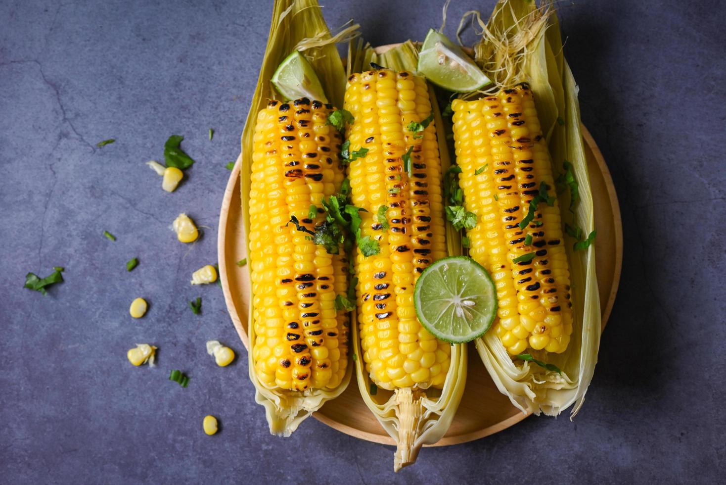 comida de maíz dulce con lima y cilantro, maíz dulce cocinado en el fondo del plato, mazorcas de maíz maduras maíz dulce a la parrilla para comida vegana cena o merienda - vista superior foto