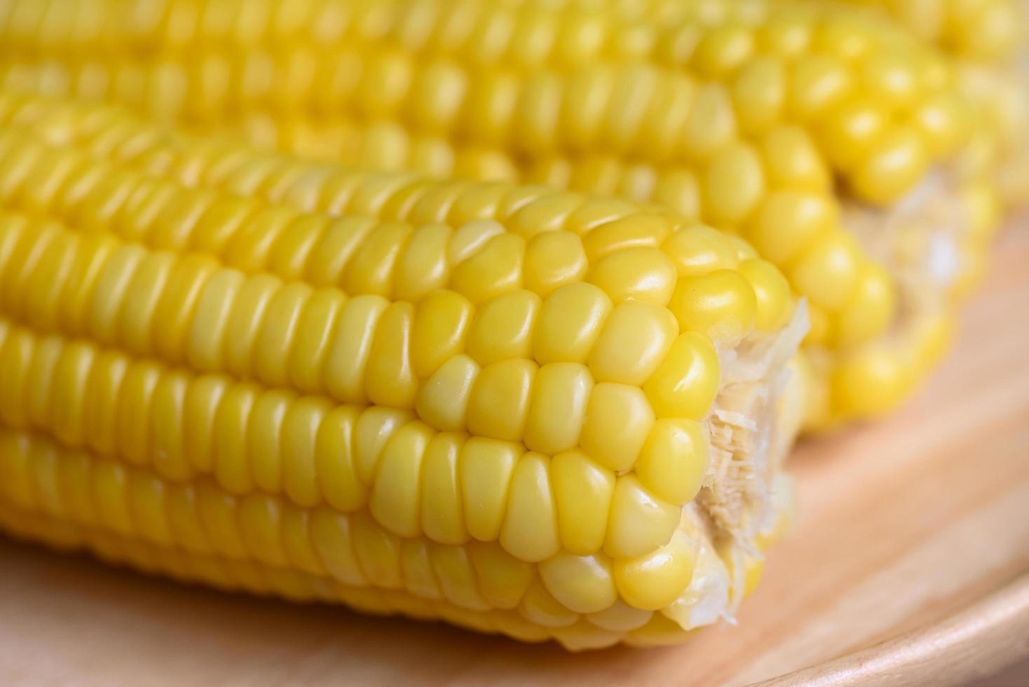 sweet corn cooked on wooden plate background, close up ripe corn cobs steamed or boiled sweetcorn for food vegan dinner or snack photo