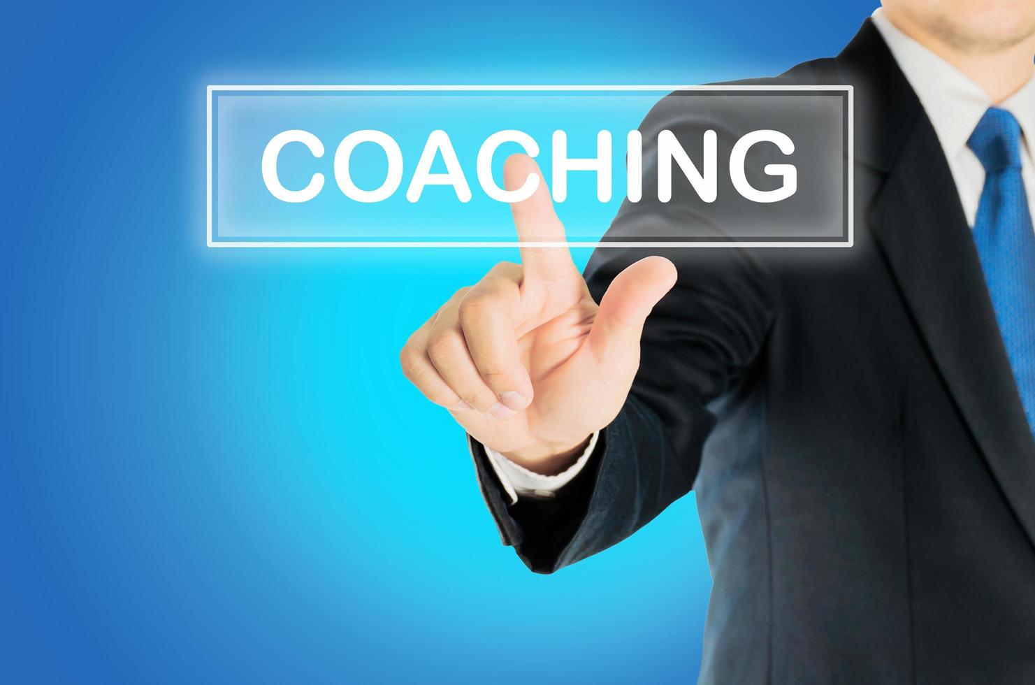Business man is pushing COACHING transparent button word over blue gradient background, business concept photo