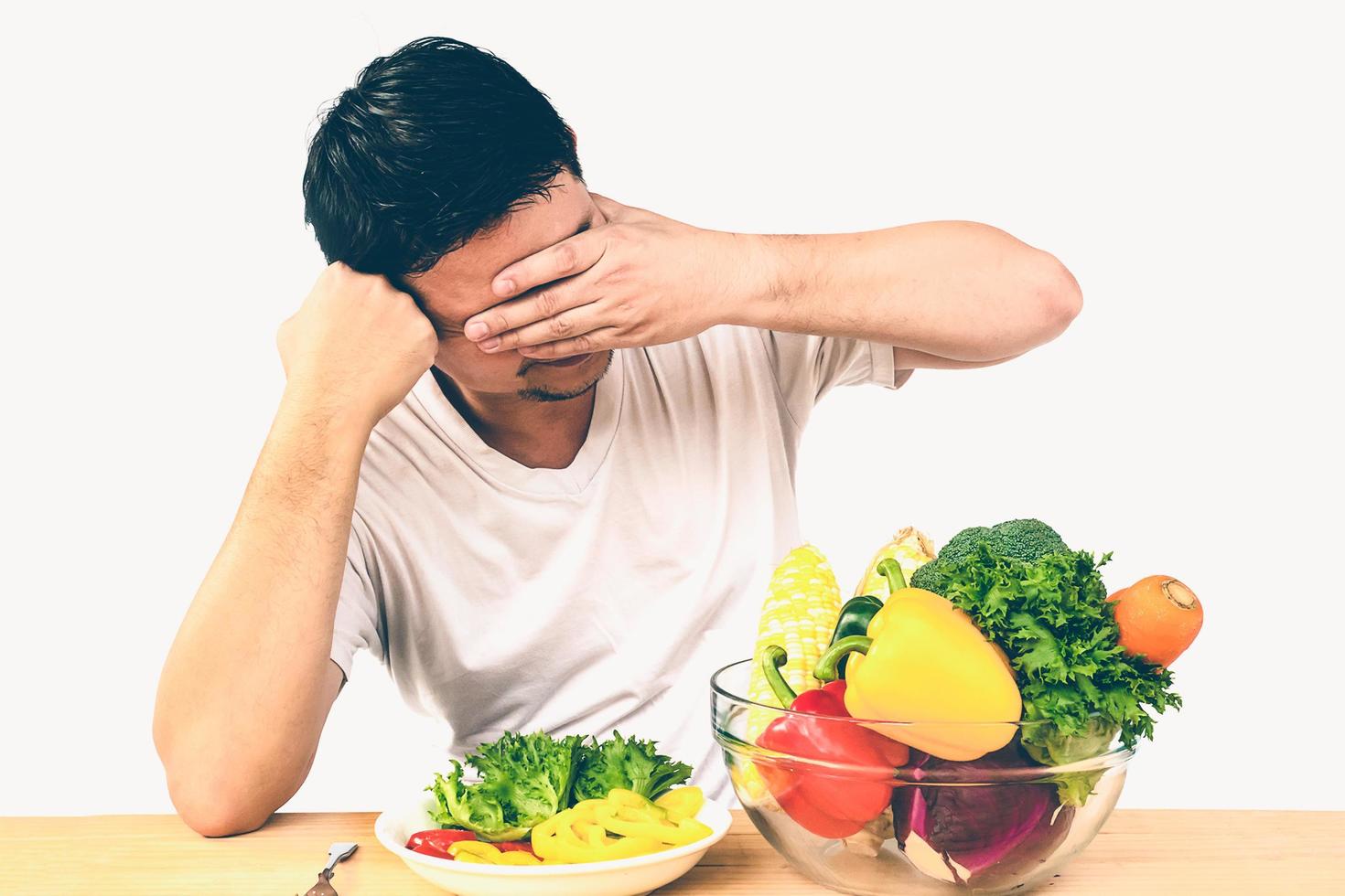 Vintage photo of Asian man showing dislike expression of fresh colorful vegetables isolated over white background