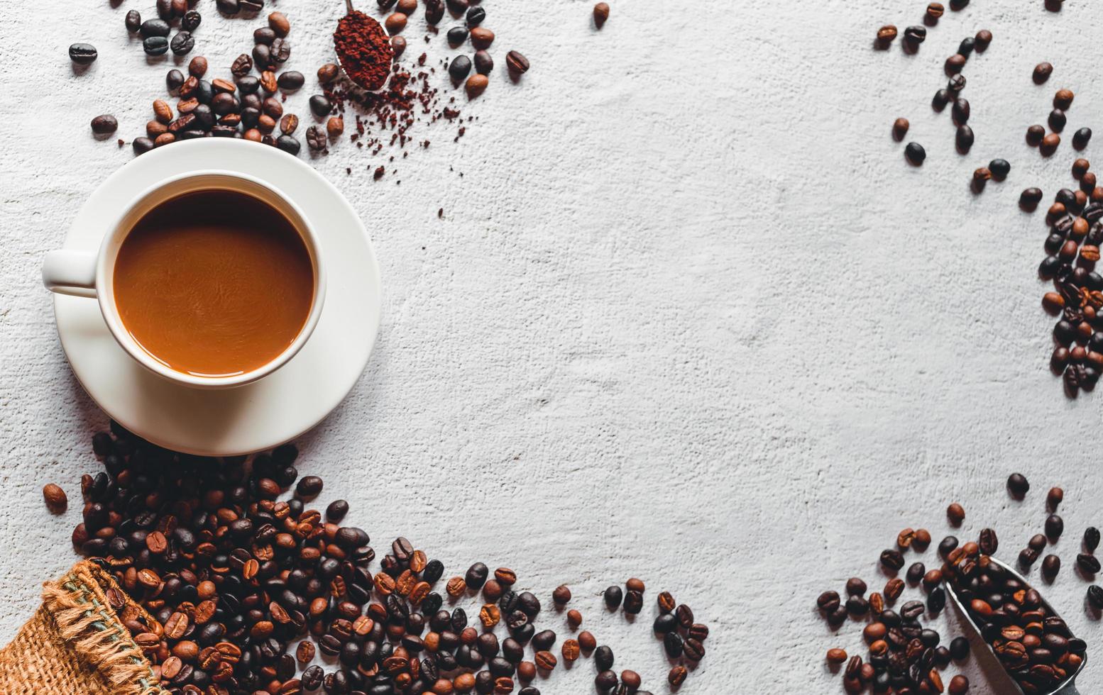 Top view of a coffee cup and coffee powder on a wooden spoon on white background. Coffee beans in the stainless steel scoop.Flat lay and copy space. photo