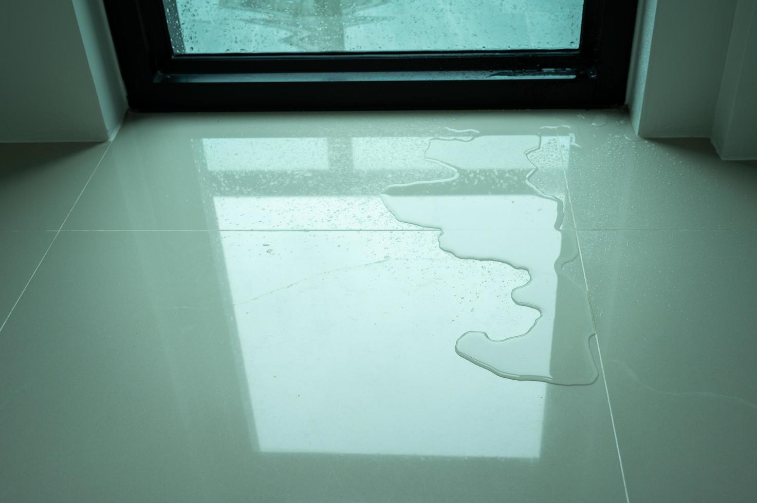 Water leaking on tile floor. Water leaks are often because of pinholes in your plumbing system or small failures in caulking or other exterior materials. photo