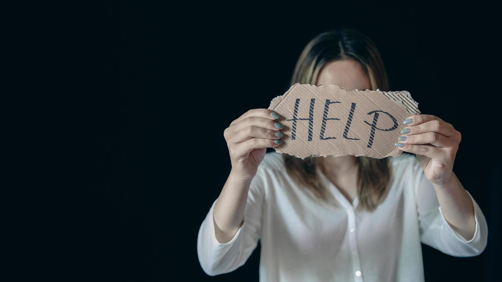 Scared and abused woman holding the paper with handwritten help sign photo