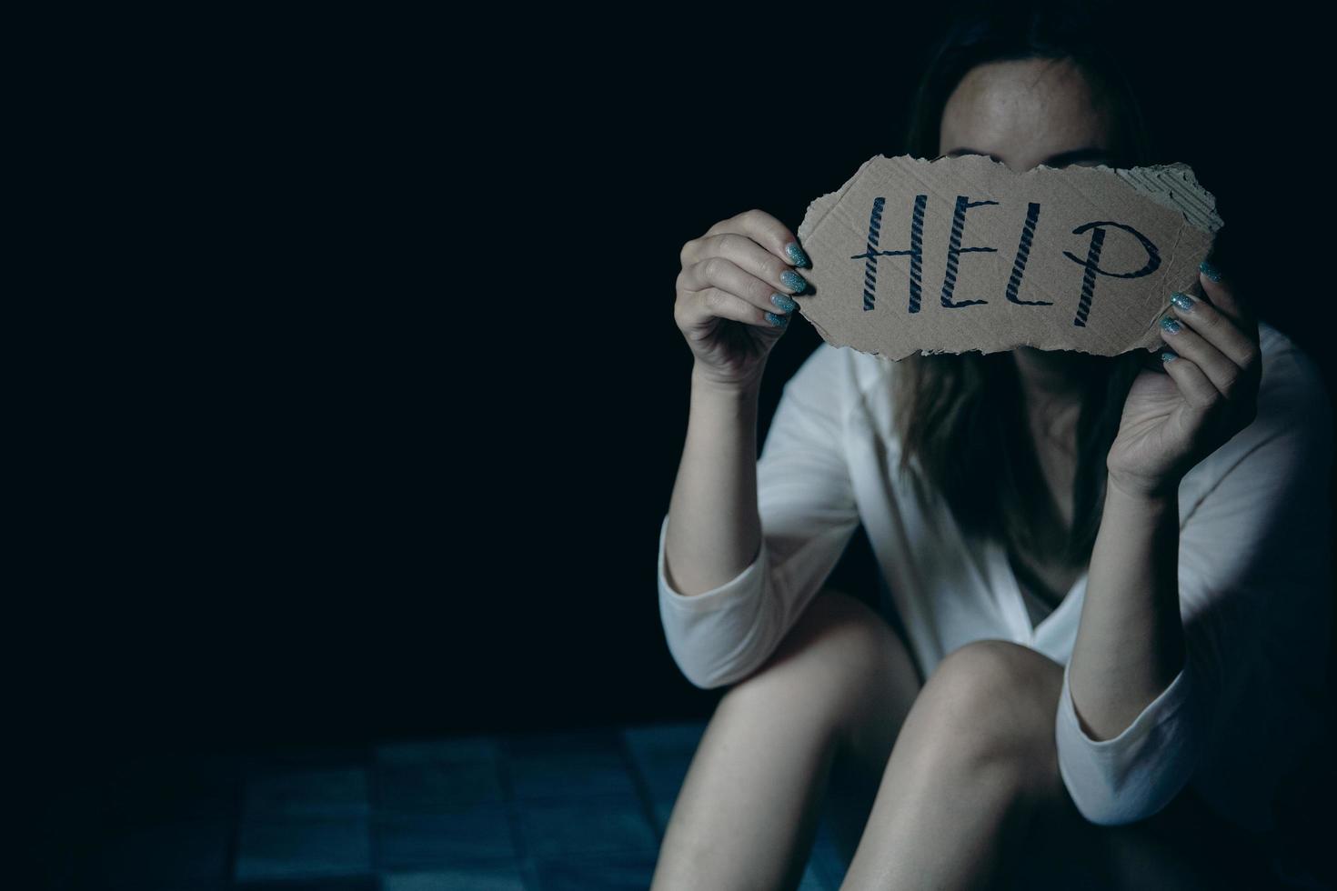 Scared and abused woman holding the paper with handwritten help sign photo