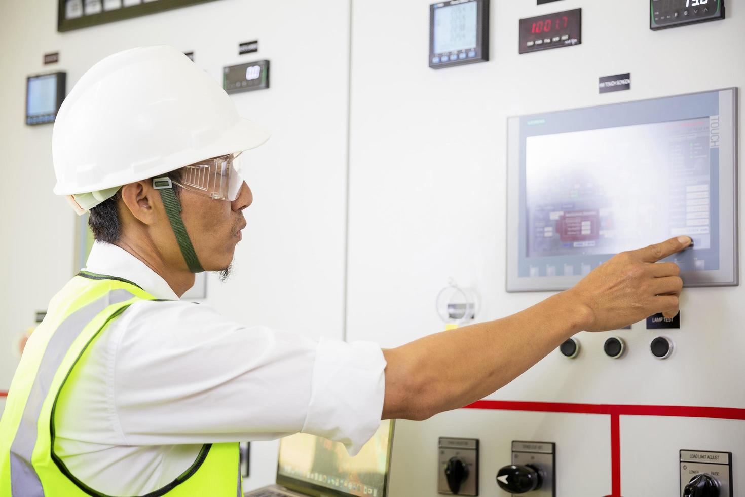 ingeniero de mantenimiento de la industria hombre uniforme y casco de seguridad bajo inspección y control del proceso de producción en la estación de fábrica. industria, ingeniero, concepto de construcción. foto