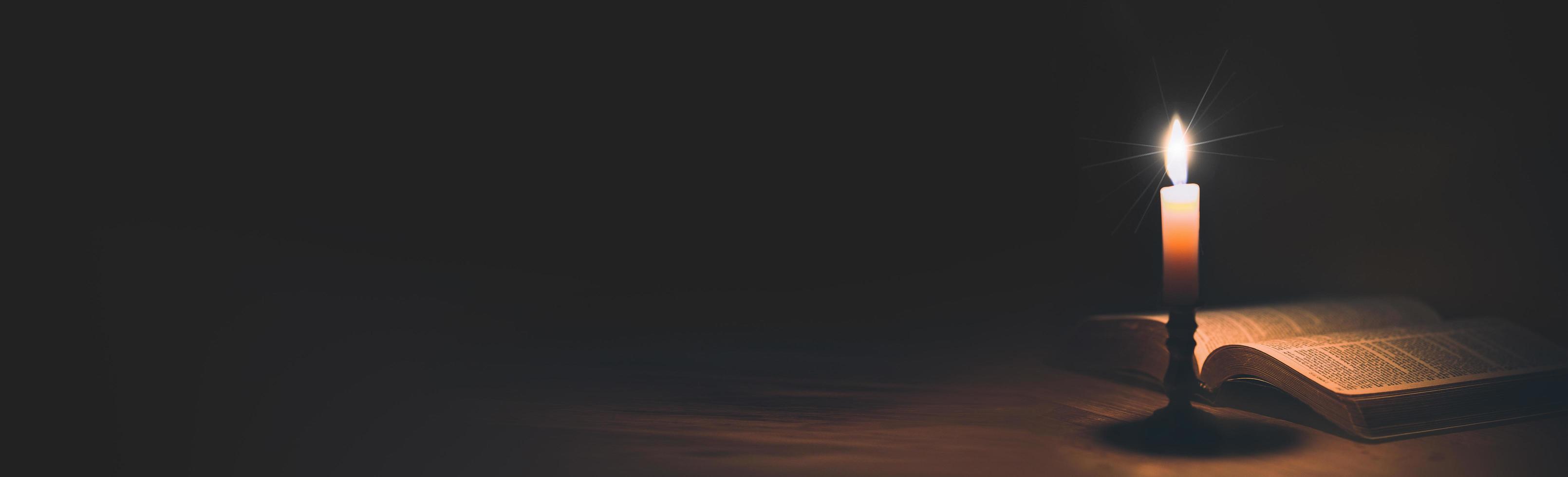 Banner image of Candle with bible on a old oak photo