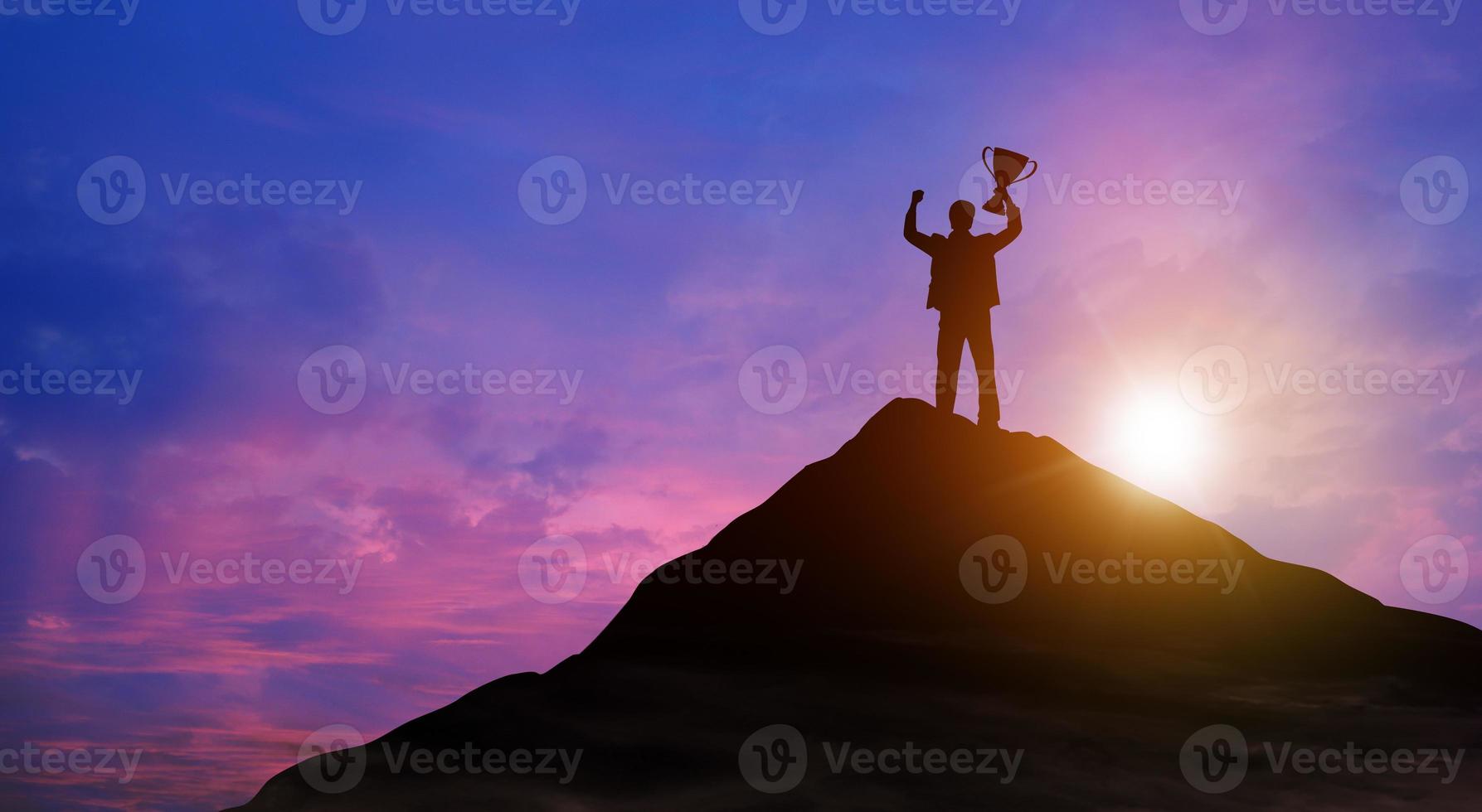 Victory businessman with trophy on top of mountain. Success, Achieving goal, Leadership, Career, Winner, and Business achievement Concept. photo