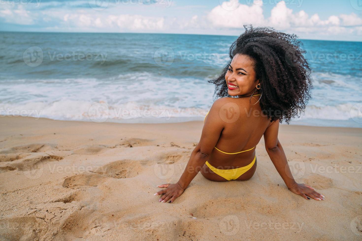 Silhouette of young woman on the beach. latin american woman sitting on the beach sand looking at camera on a beautiful summer day photo